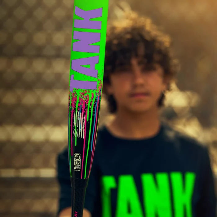 A boy in a black shirt with bold green “TANK” lettering stands behind a Soldier Sports 2026 Soldier Tank Double Wall (-10) 2 3/4″ USSSA Baseball Bat: Y-10-26-2 (USED), which features matching TANK graphics and advanced double wall technology. An out-of-focus chain-link fence appears in the background.