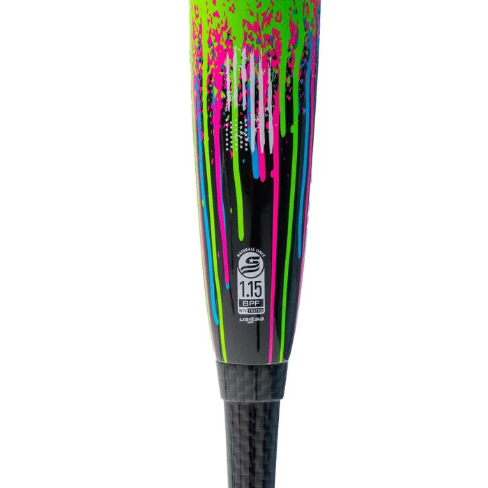 Close-up of the handle of a Soldier Sports 2026 Soldier Tank Double Wall (-10) 2 3/4″ USSSA Baseball Bat: Y-10-26-2 (USED), featuring bright green, pink, and blue paint splatters and stripes. The 1.15 BPF USSSA certification stamp sits above the carbon fiber grip, highlighting its composite barrel construction for enhanced performance.