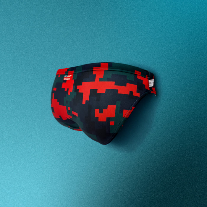 Pixelated swim briefs with red and green pattern on a teal background