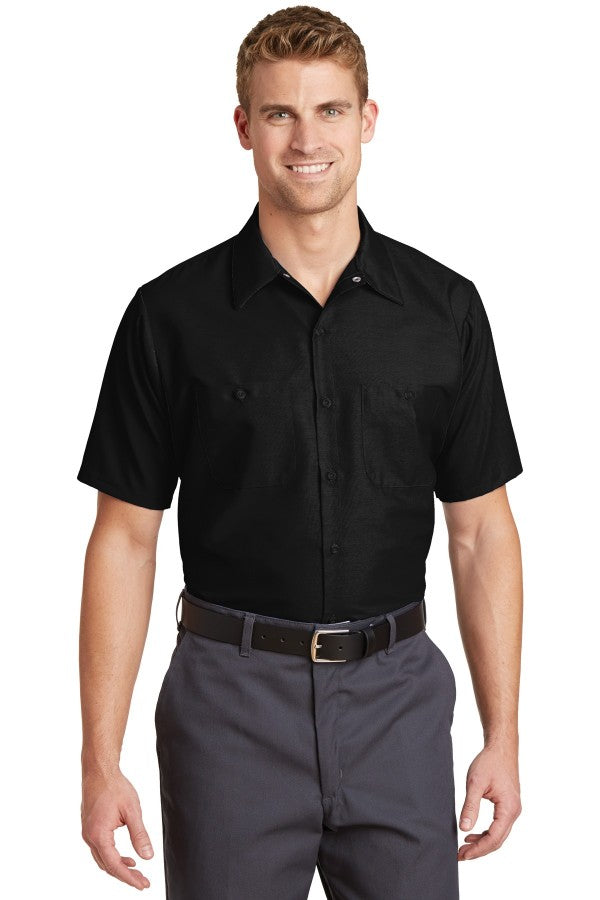 Male model wearing Red Kap Men's Short Sleeve Industrial Work Shirt in black, featuring button-front closure and dual chest pockets.