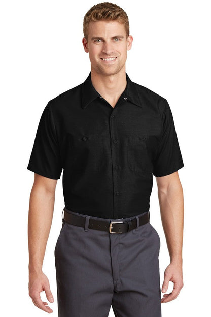 Male model wearing Red Kap Men's Short Sleeve Industrial Work Shirt in black, featuring button-front closure and dual chest pockets.